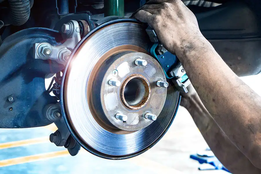 A mechanic installing new brakes on a car in Decatur, IL