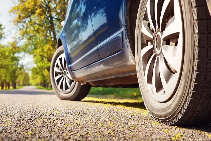 Creekmur Car Care—A car’s tires on an asphalt road during summer in Decatur, IL.