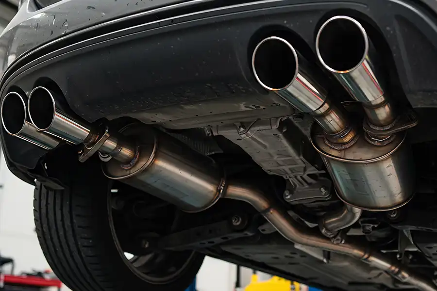Creekmur Car Care—A close-up view of a quad exhaust system on a silver car in a Decatur, IL auto shop.